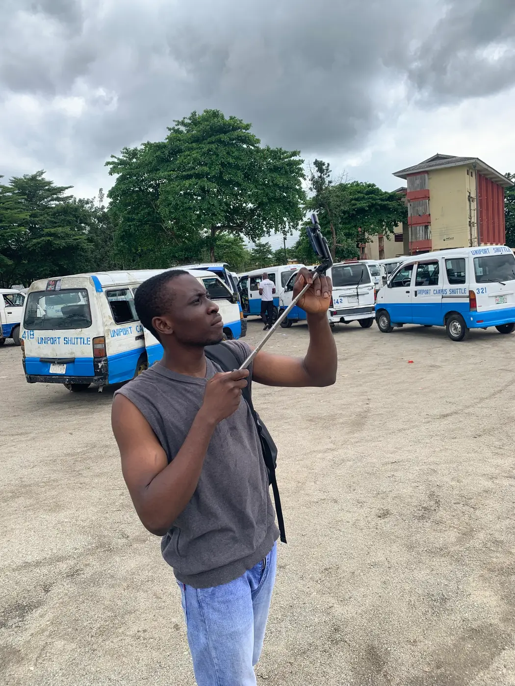 odii holding a phone on a stick up high to film the shuttles at the motor park